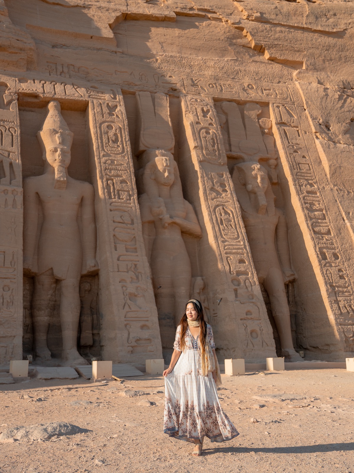 Woman standing beside carved figures at Abu Simbel in Egypt