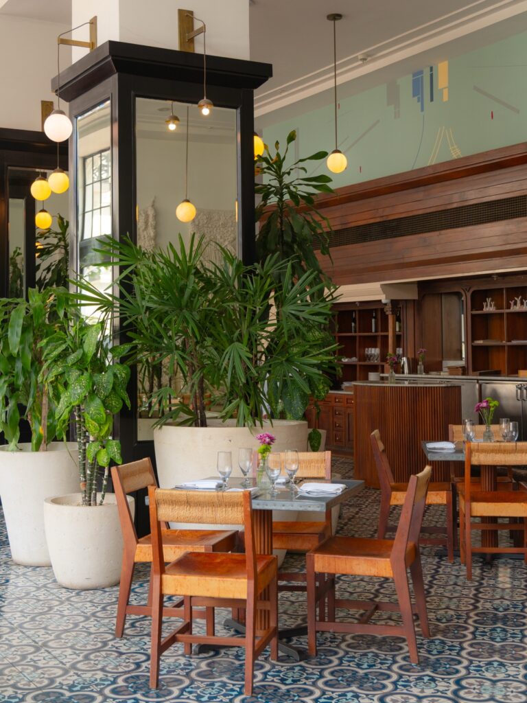 Dining room at American Trade Hotel with patterned blue tile floor, globe pendant lights, and lush plants in Casco Viejo Panama