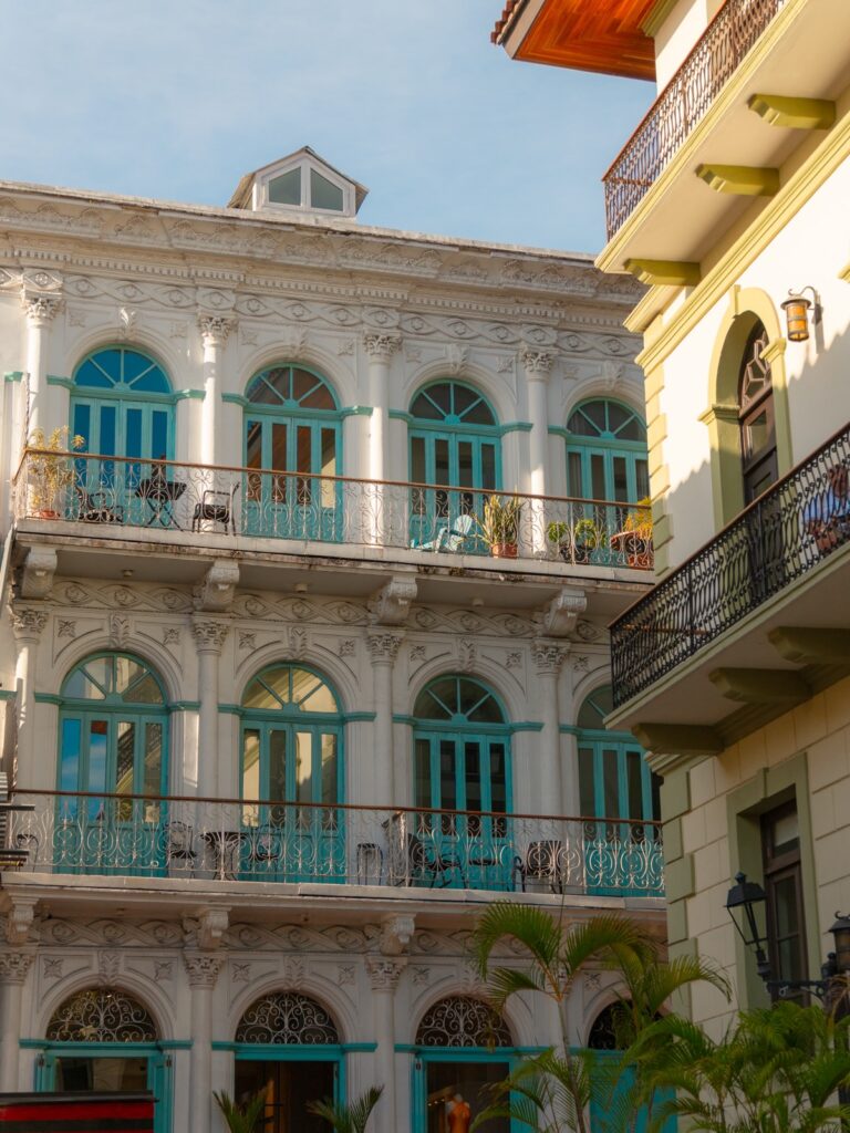 White colonial building with ornate turquoise window shutters and wrought iron balconies in Casco Viejo Panama