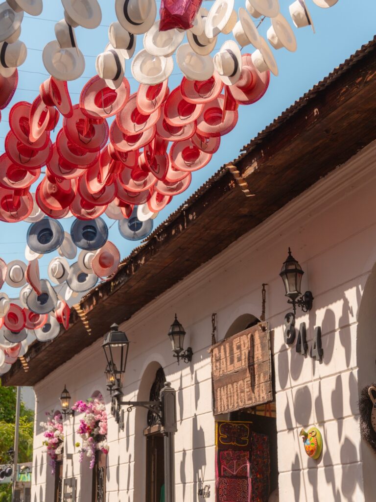 Rows of colorful Panama hats hanging overhead outside shops on a street in Casco Viejo, Panama