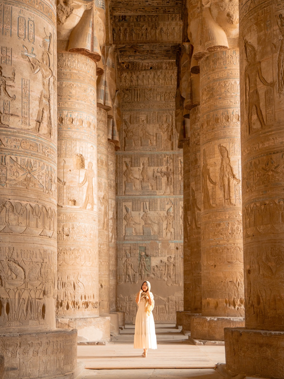 Woman standing between painted columns at Dendera Temple in Egypt
