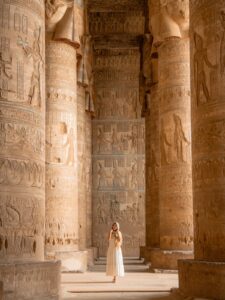 Woman standing among hieroglyphic-covered columns inside Dendera Temple in Egypt