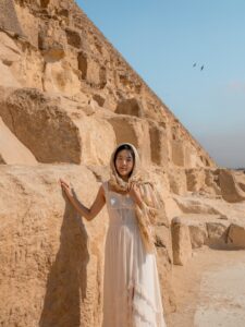 Woman in white dress standing at the base of the Great Pyramid of Giza in Egypt