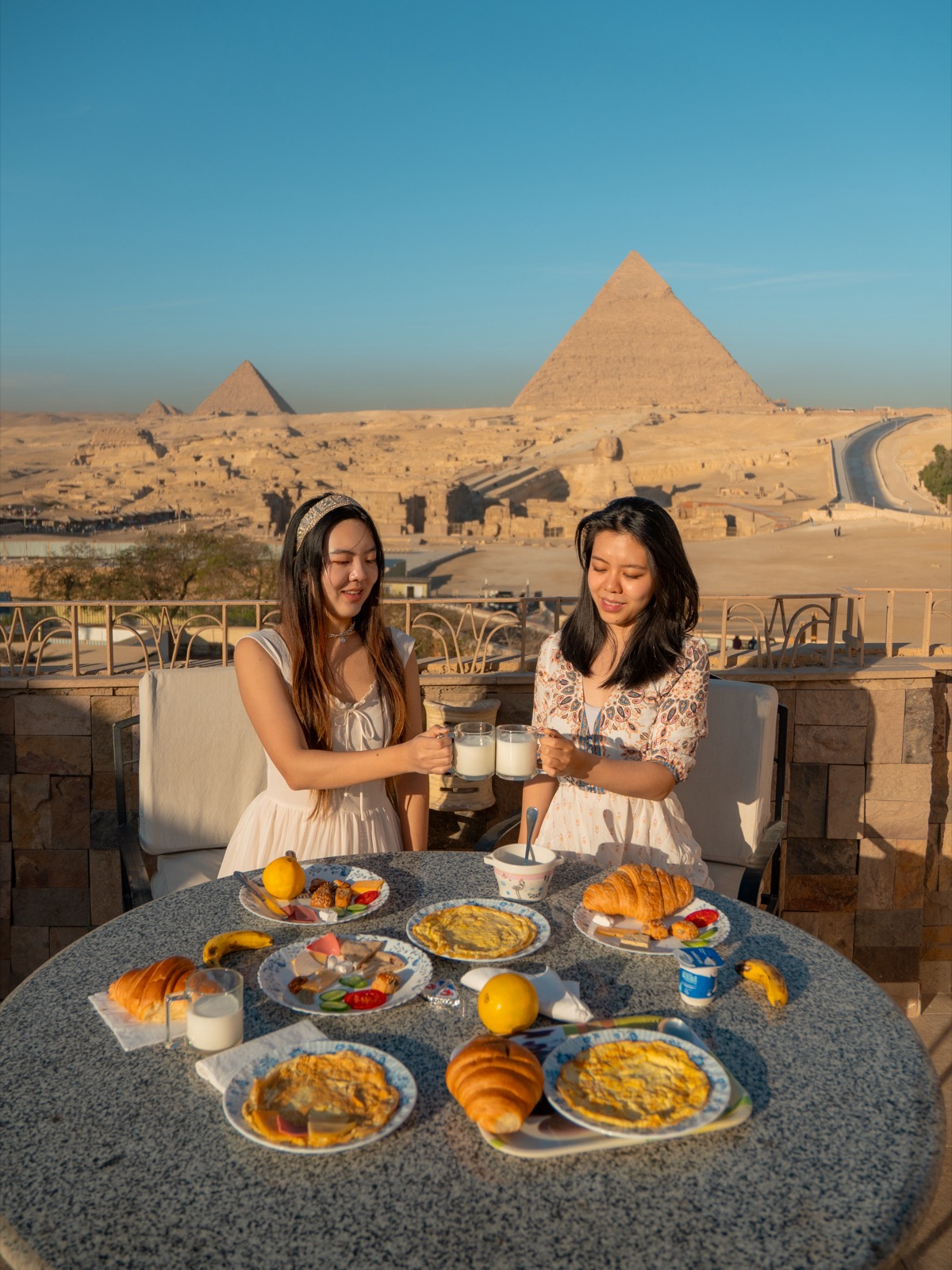 Amy and a family member having breakfast at Guardian Guest House with the Pyramids of Giza behind them
