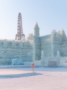 Person standing in front of a massive ice castle at the Harbin Ice and Snow World festival
