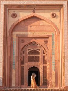 Woman standing in an ornate red sandstone archway at Fatehpur Sikri near Agra, India