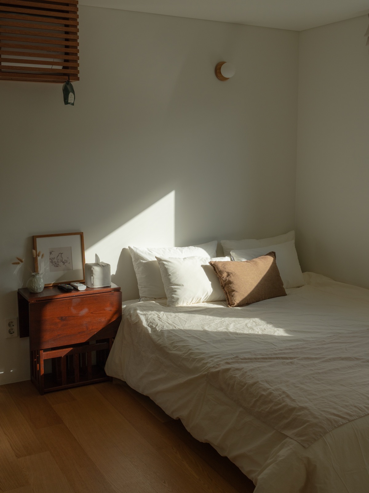 Sunlit hanok guesthouse bedroom with wooden window blinds and crisp white bedding in Jeonju, South Korea
