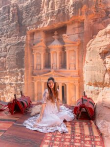 Woman sitting on a rug overlooking the Treasury at Petra, Jordan at golden hour