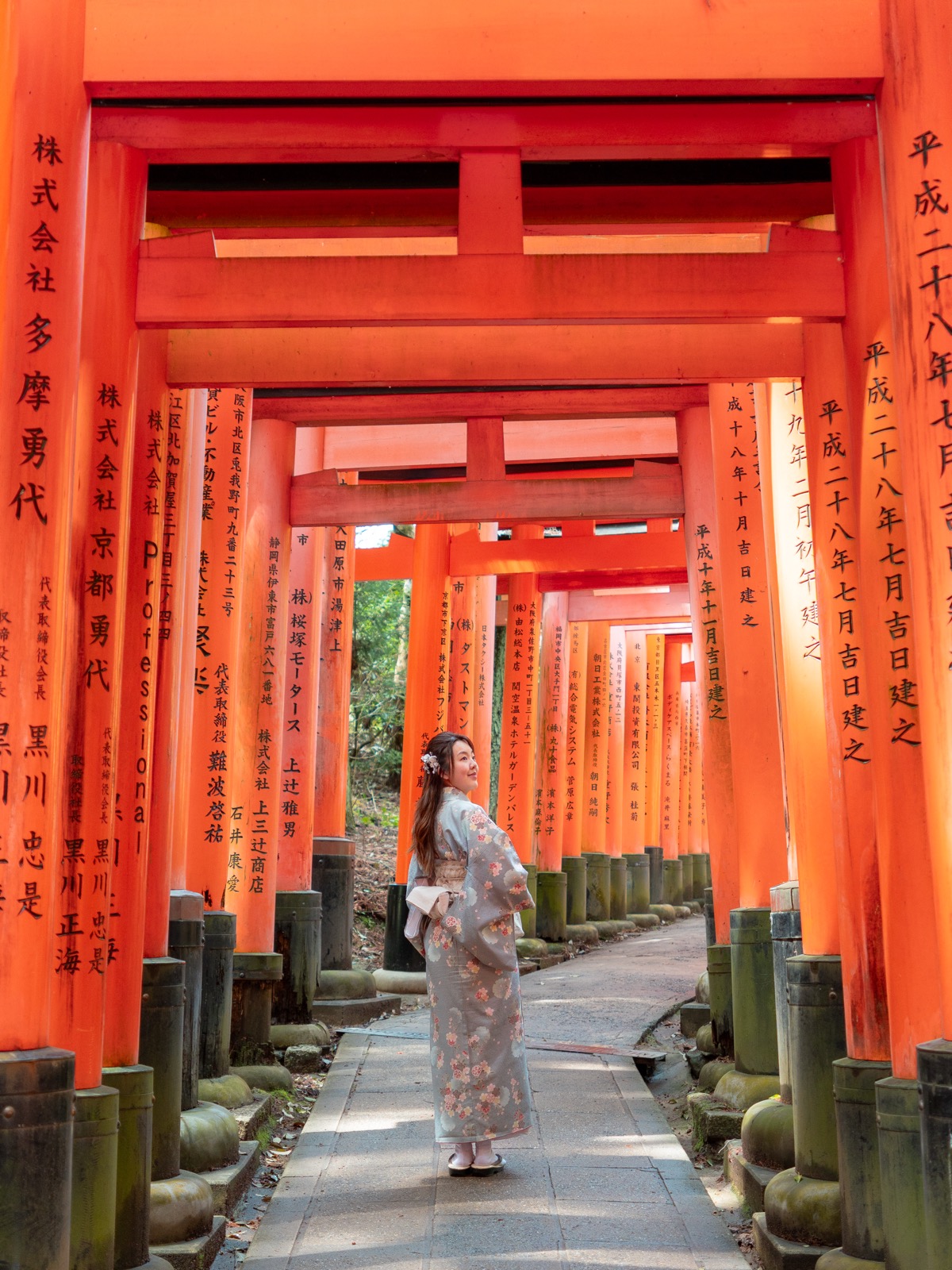 Woman in kimono standing inside the vermillion torii gate tunnel at Fushimi Inari Shrine