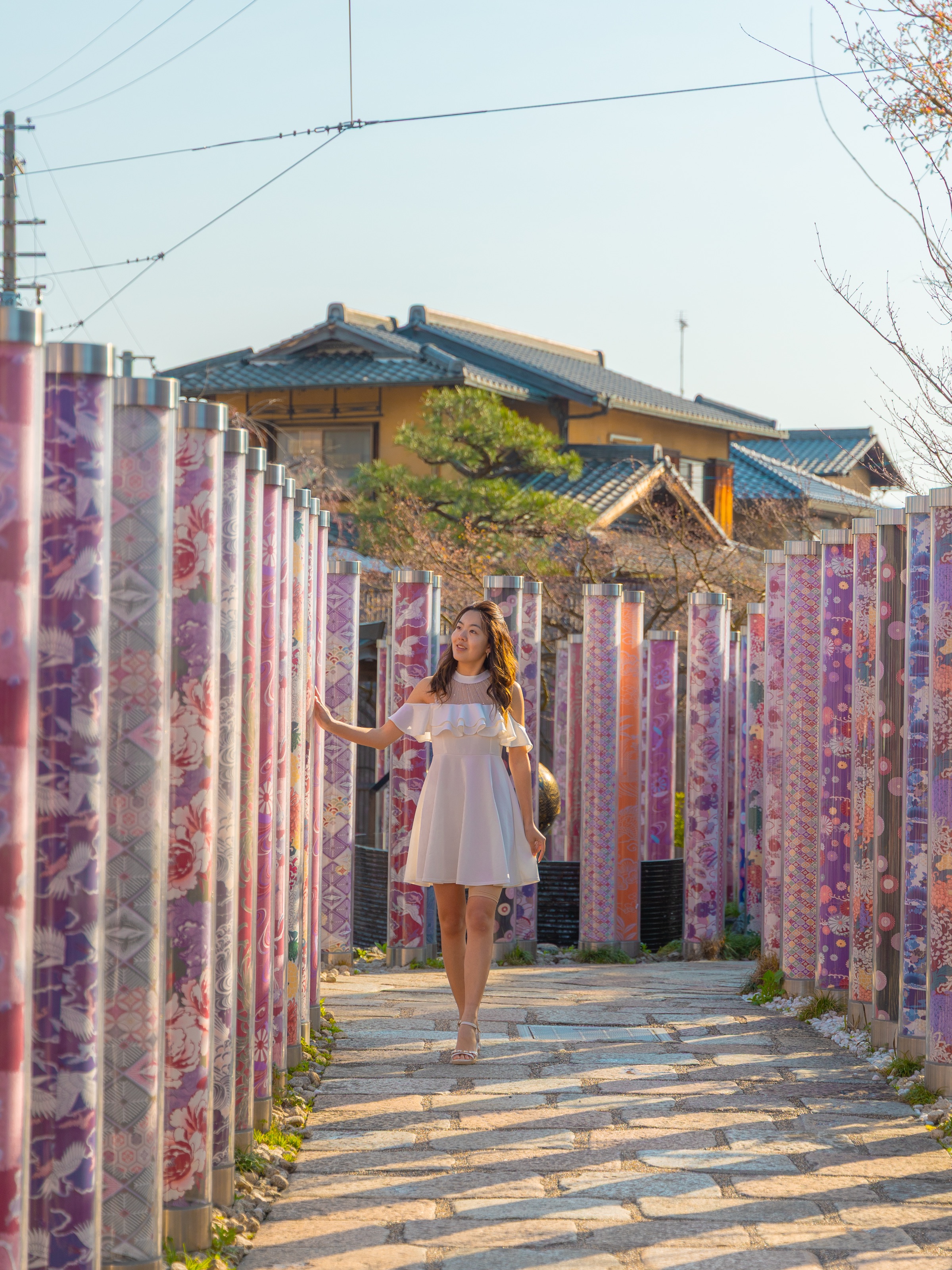 Walking between colorful kimono fabric pillars at the Kimono Forest installation at Randen Arashiyama Station