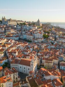 Drone shot of Lisbon Alfama neighborhood with orange rooftops at golden hour