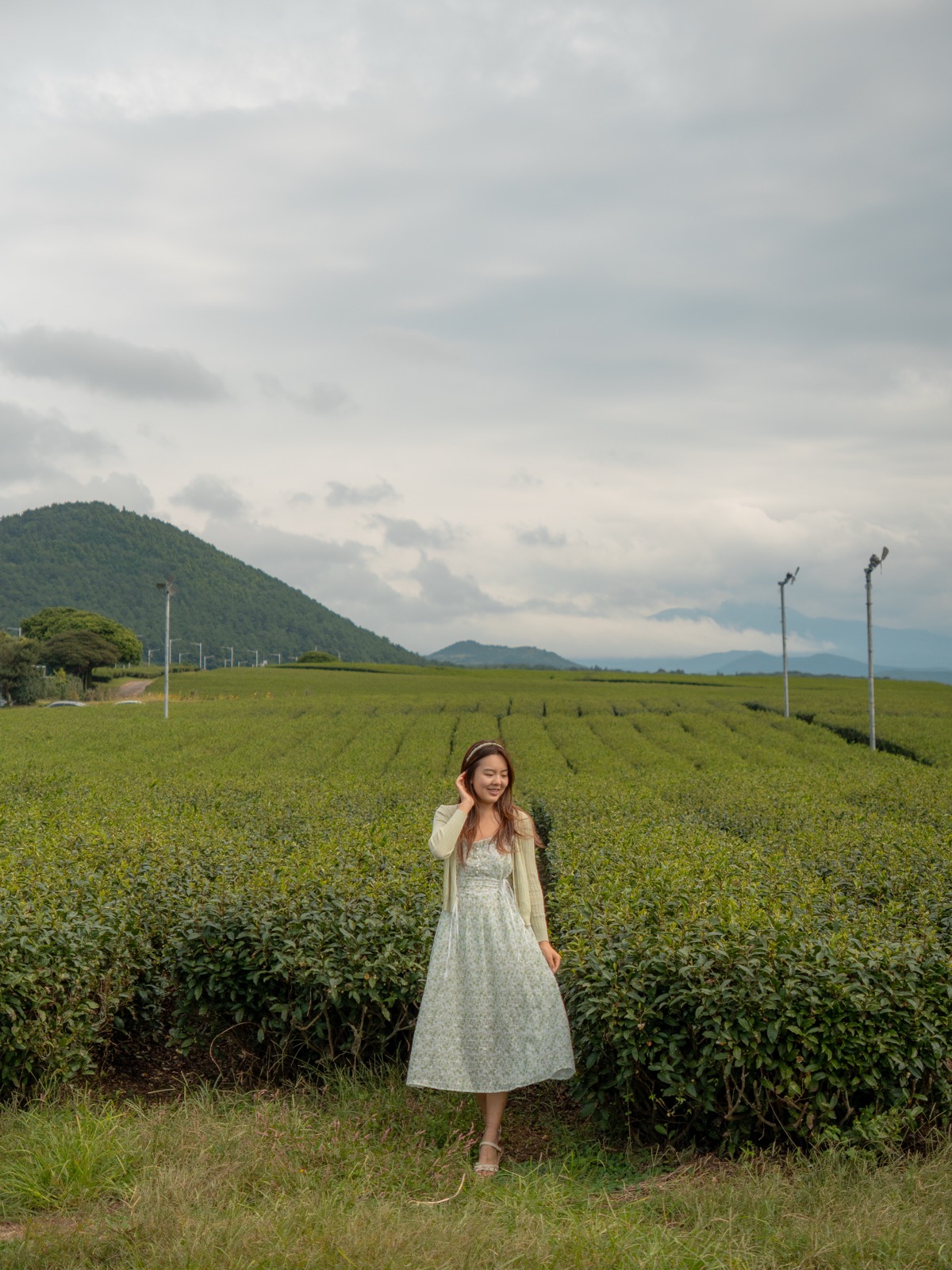 Woman in a light dress standing in green tea fields at O Sulloc Tea Museum on Jeju Island, South Korea