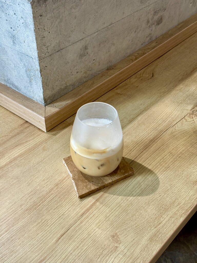 Iced latte in a frosted glass on a wooden counter at Sisu Coffee in Casco Viejo, Panama